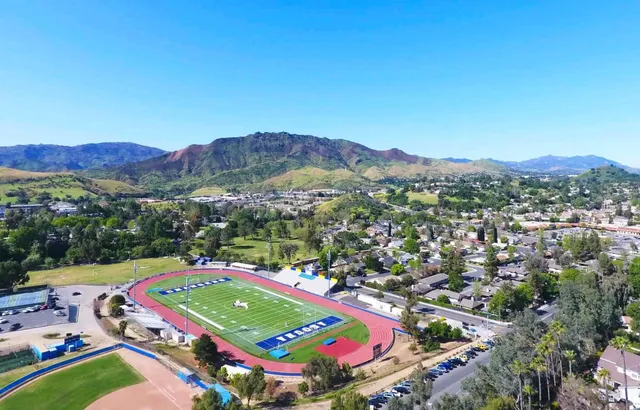 Il campo sportivo del Las Virgenes Unified School District con dintorni verdi e montagne sullo sfondo sotto un cielo azzurro.