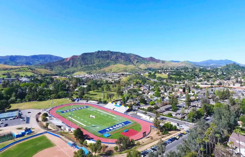 Il campo sportivo del Las Virgenes Unified School District con dintorni verdi e montagne sullo sfondo sotto un cielo azzurro.