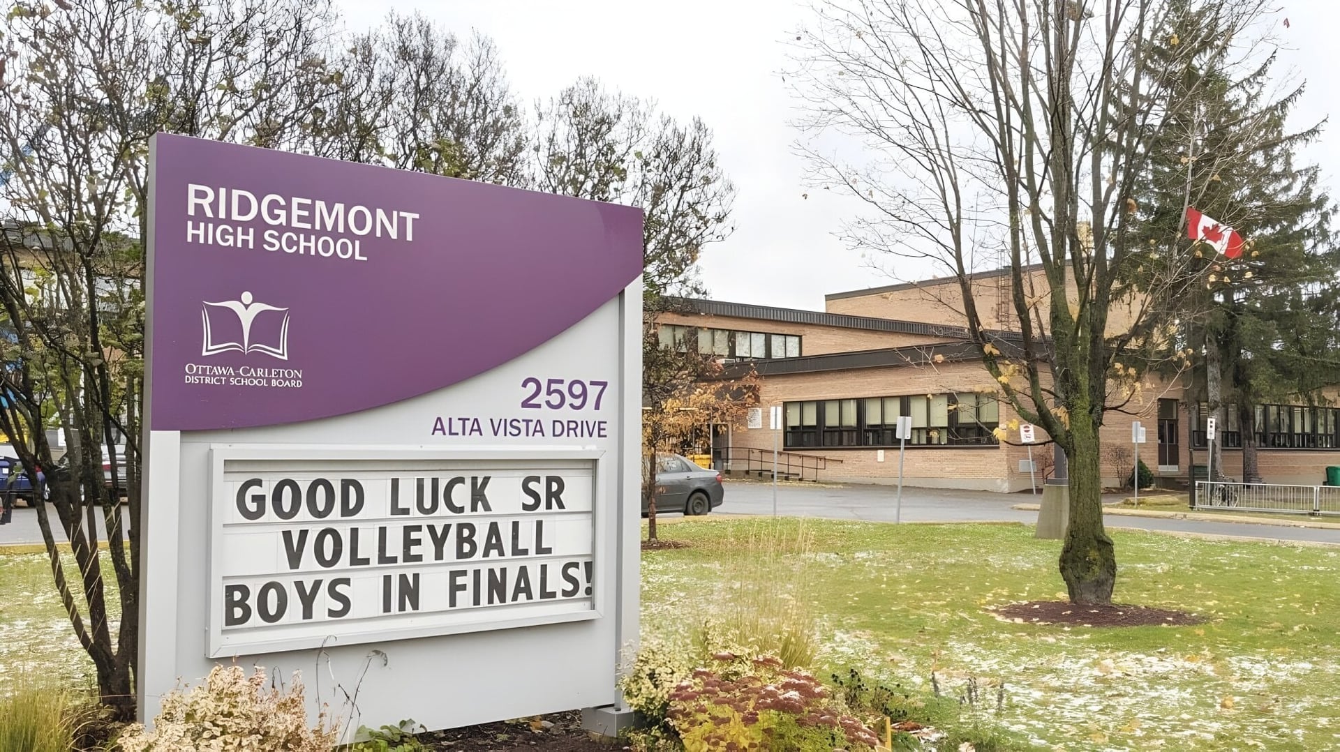 Vista exterior de Ridgemont High School con un cartel de felicitación para el equipo de voleibol masculino en la final.