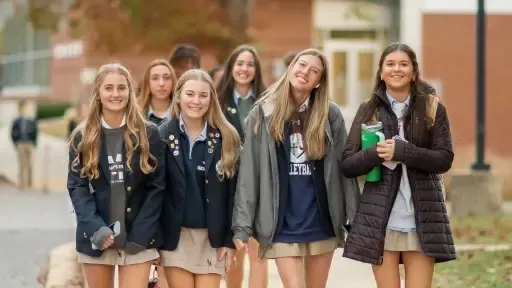 Un grupo de alumnas está junto y sonríe en el campus de St. Mary's Ryken High School.