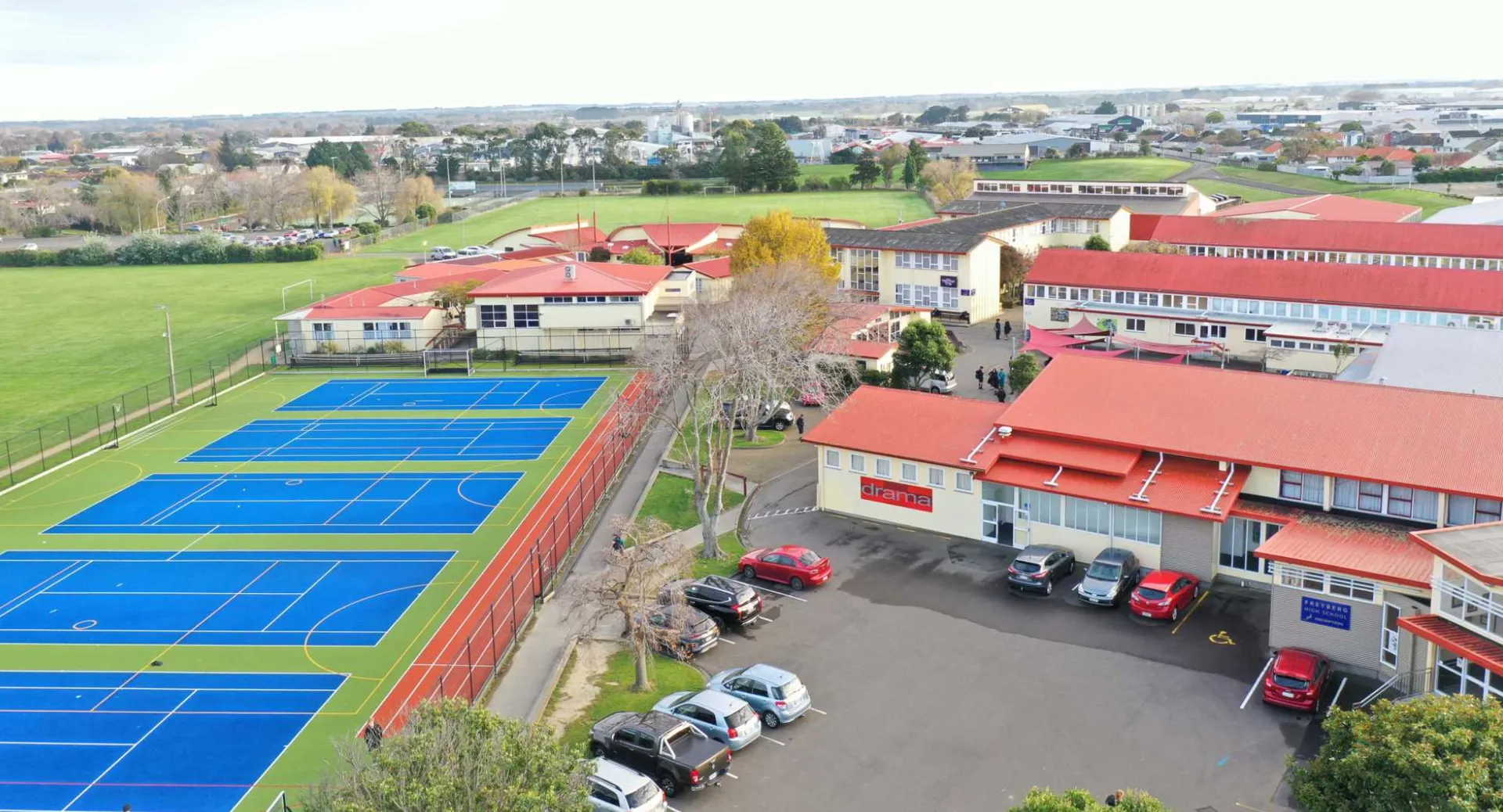 Il campo da tennis all'interno del campus della Freyberg High School mostra campi all'aperto colorati con edifici sullo sfondo.