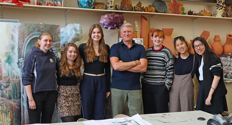 Un gruppo di studentesse e studenti con degli adulti in una stanza artisticamente decorata della The Mount School York.