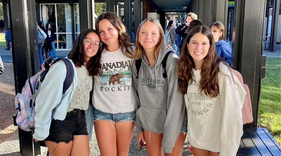 Un gruppo di studentesse in posa davanti a un edificio con grandi finestre nel campus della San Domenico School.