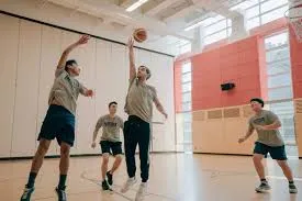 Estudiantes de Pattison High School juegan al baloncesto en el pabellón deportivo luminoso con grandes ventanas.