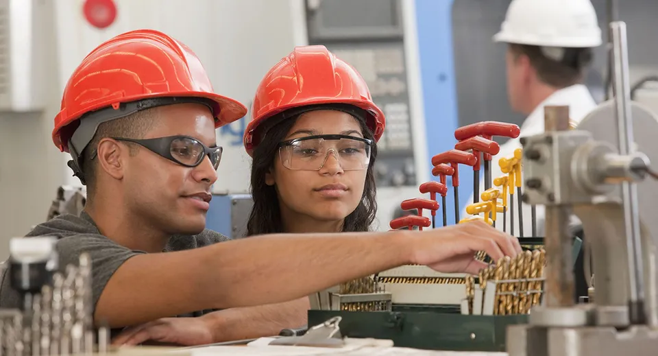 Due studenti della Technical Vocational High School esaminano degli attrezzi in officina.