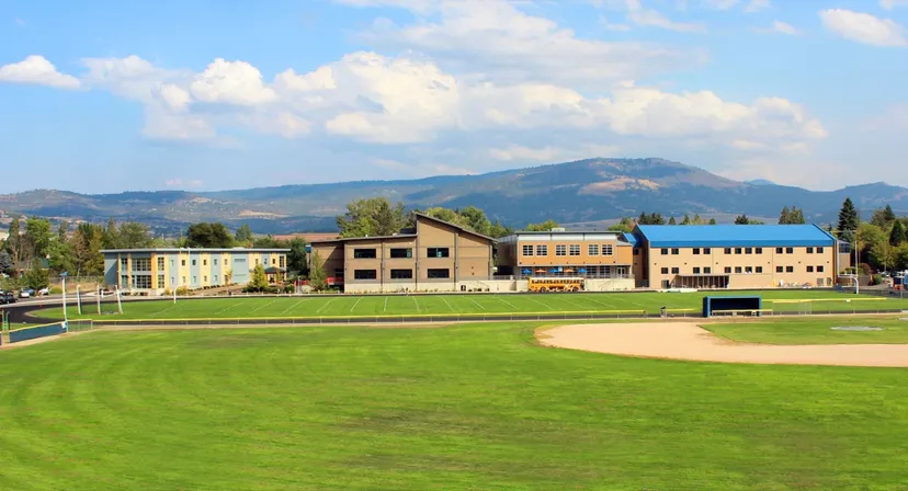 Un prato davanti a edifici colorati e montagne all'interno del campus della St. Mary's School.
