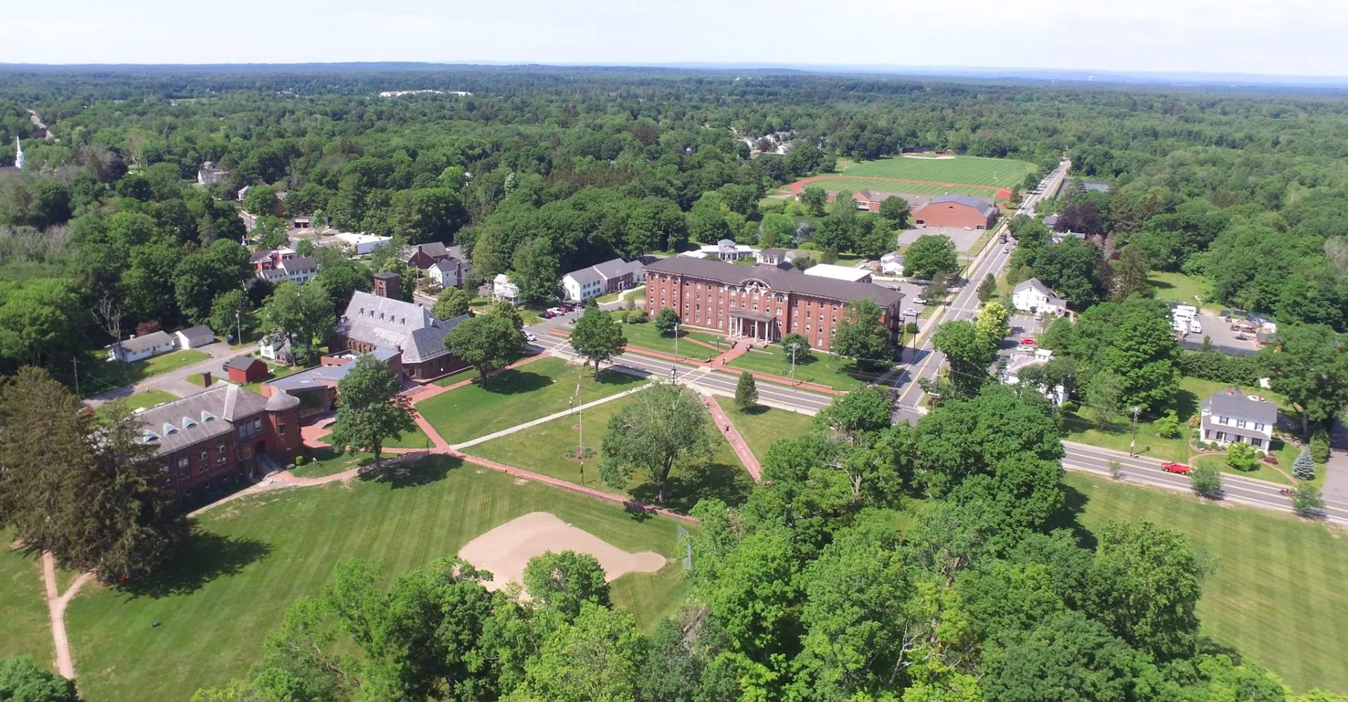 Vista aerea dell'ampio campus della Wilbraham & Monson Academy con edifici storici e moderni immersi nel verde dei boschi.
