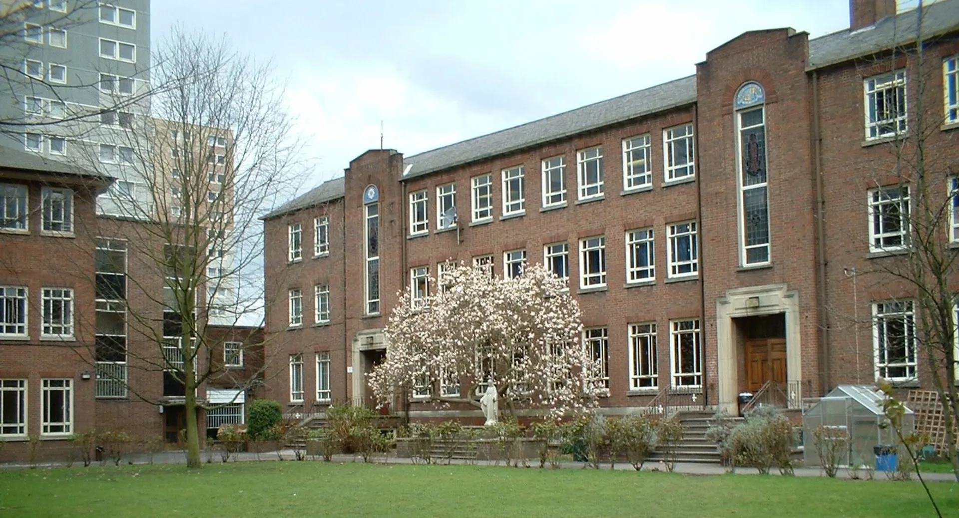 Edificio in mattoni a più piani con albero in fiore e prato nel campus del Loreto College Cavan.