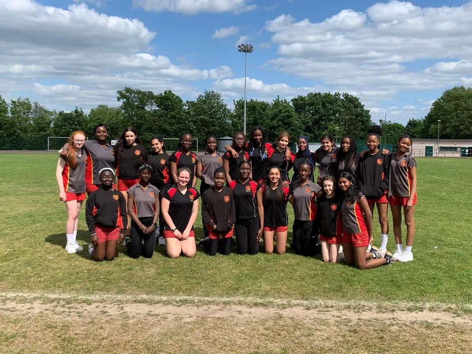 Un gruppo di studenti della Townley Grammar School posa insieme su un campo sportivo con uno stadio sullo sfondo.