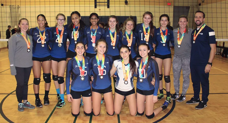 Un gruppo di giovani pallavoliste del Birchmount Park Collegiate Institute in una palestra con medaglie e trofei.