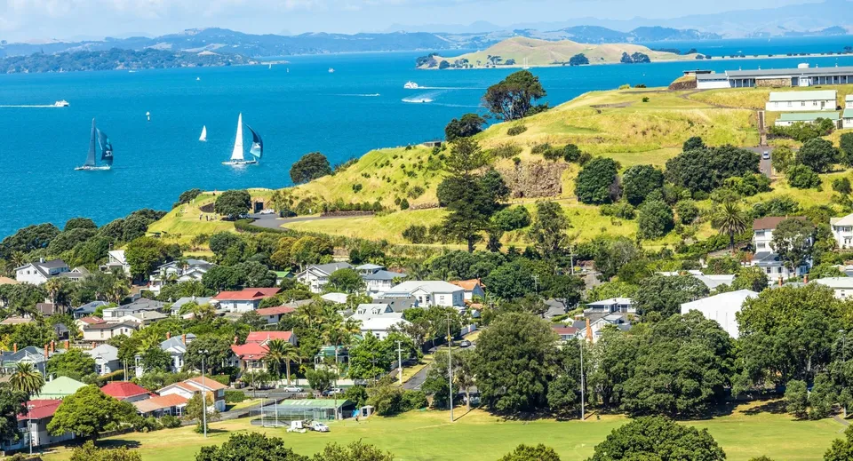 Una pittoresca città costiera con barche a vela e colline verdi sullo sfondo, vicino alla Devonport High School.