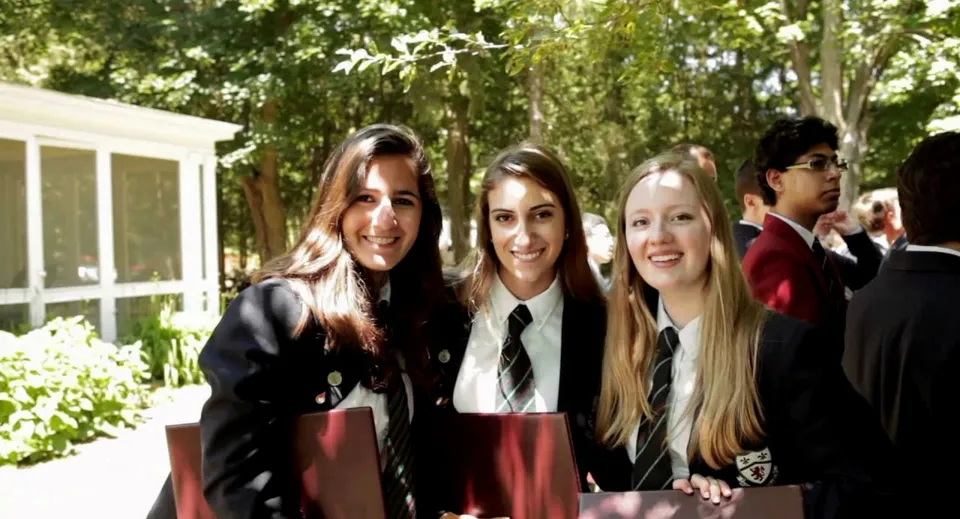 Un gruppo di studentesse posa nel verde sul campus dell'Ashbury College davanti ad alberi e un edificio.