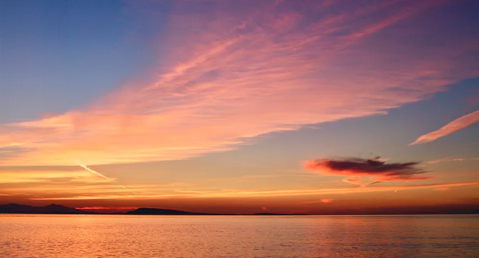 Un tramonto con nuvole rosa e arancioni sul mare a Qualicum Beach vicino alla Kwalikum Secondary School.