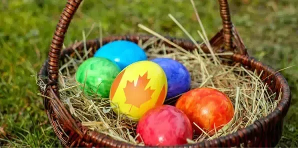 Cesta de mimbre con huevos de Pascua coloridos, uno con la hoja de arce