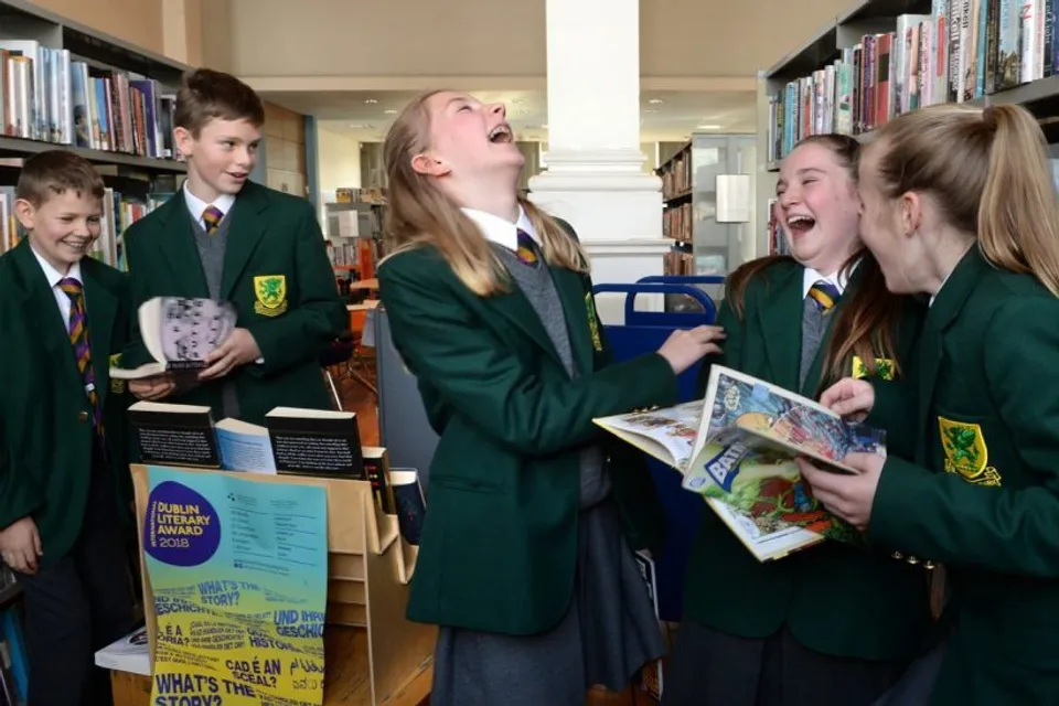 Studenti della Sandford Park School in divisa verde ridono insieme nella biblioteca.