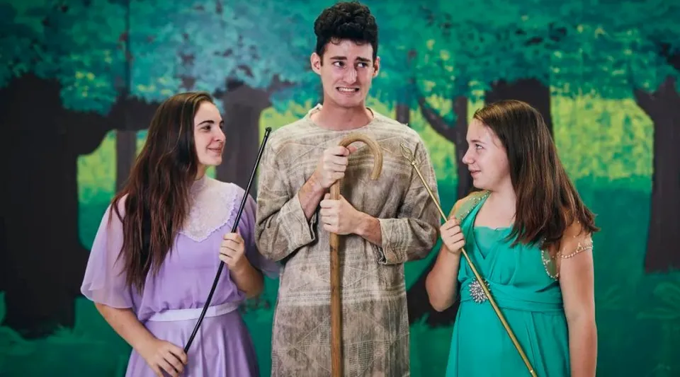 Tre studenti della Shalom Christian Academy sono insieme nell'area verde esterna con alberi sullo sfondo.