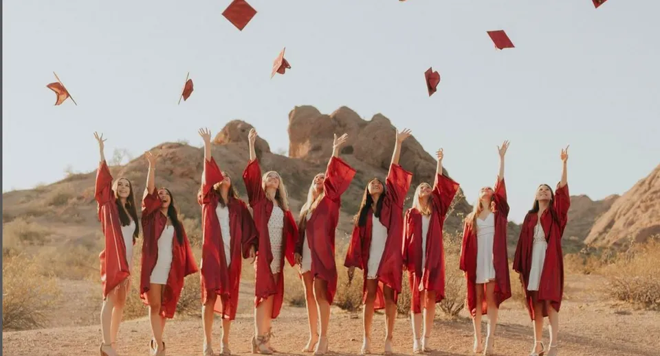 Un gruppo di persone vestite di rosso in piedi davanti a un paesaggio montuoso nel campus dello Scottsdale Unified School District.