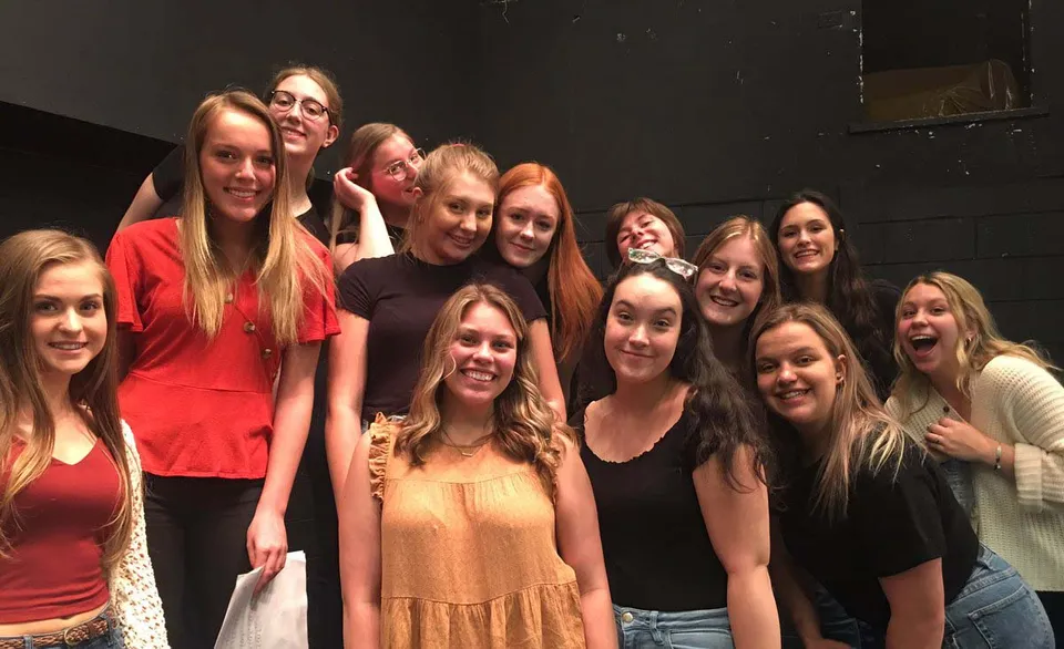 Un gruppo di studentesse della Holy Heart of Mary High School in posa in una stanza buia.