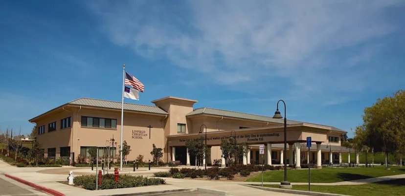 L'edificio a due piani della Linfield Christian School con la bandiera americana e sudcoreana nel cielo limpido.
