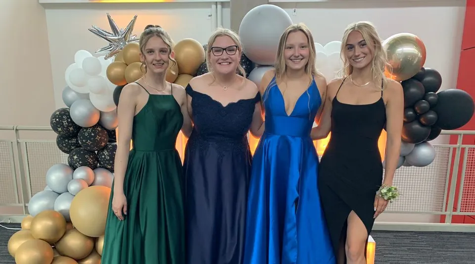 Quattro studentesse della St. Timothy High School posano davanti a uno sfondo di palloncini colorati.