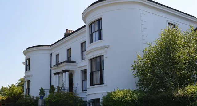 L'edificio bianco con dettagli architettonici curvi nel campus della Rathdown School è circondato da una rigogliosa area verde.