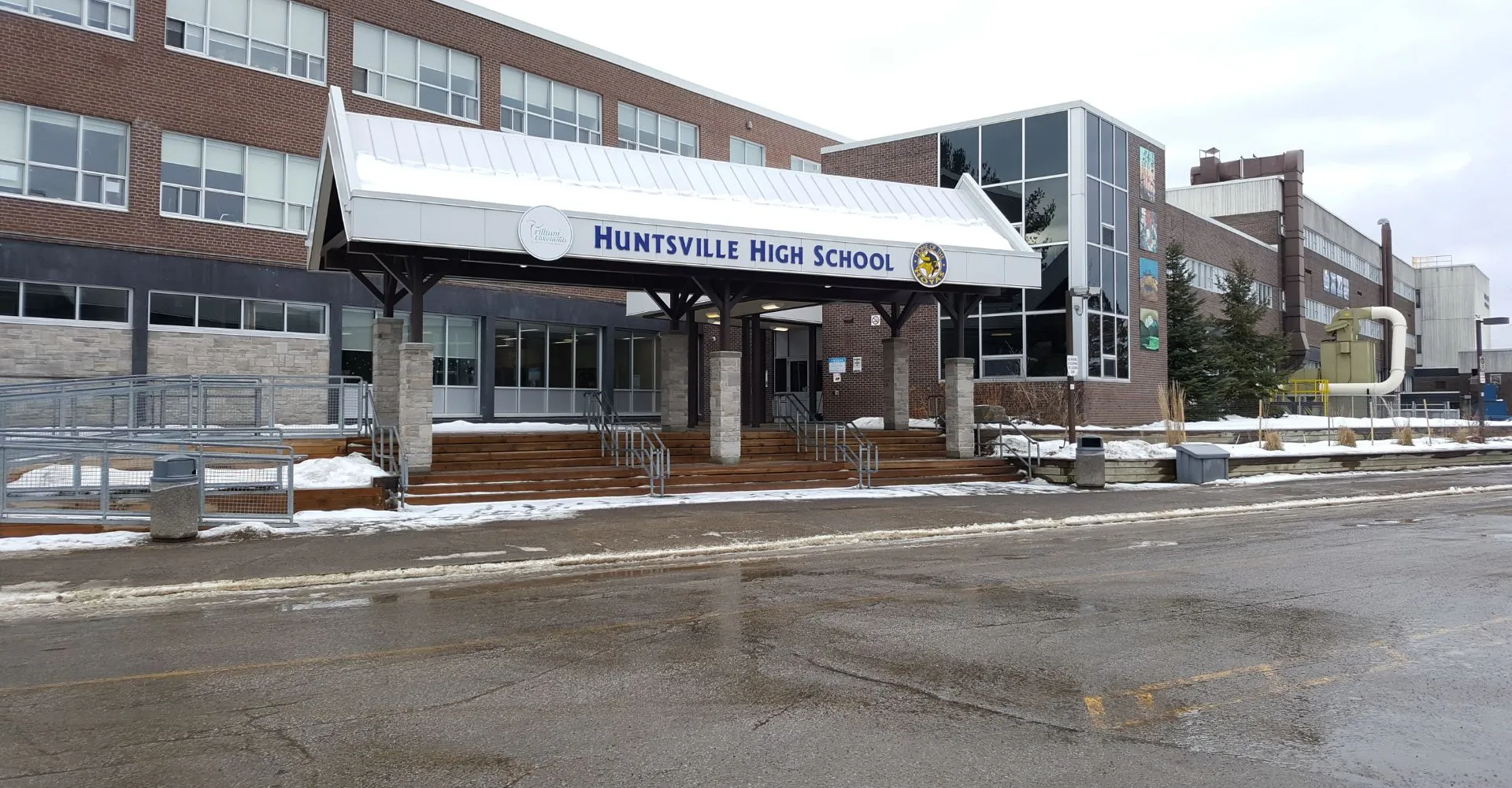 Il grande edificio in mattoni della Huntsville High School è immerso in un paesaggio innevato sotto un cielo nuvoloso.