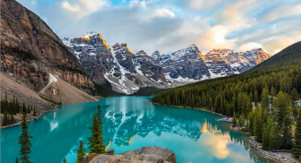 Un lago di montagna dalle acque turchesi circondato da foreste di pini e cime innevate nei pressi della George Elliot Secondary School.