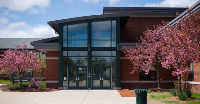Das moderne Gebäude des Hopkinton Public School District mit rotem Backstein und blühenden Kirschbäumen im Vordergrund.