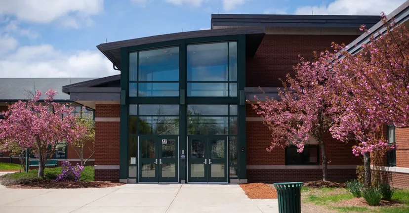 L'edificio moderno del Hopkinton Public School District in mattoni rossi con ciliegi in fiore in primo piano.