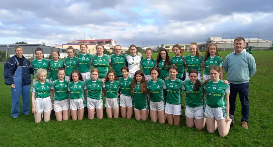 Un gruppo di giovani atlete in maglia verde posa insieme su un campo del campus del Hazelwood College.