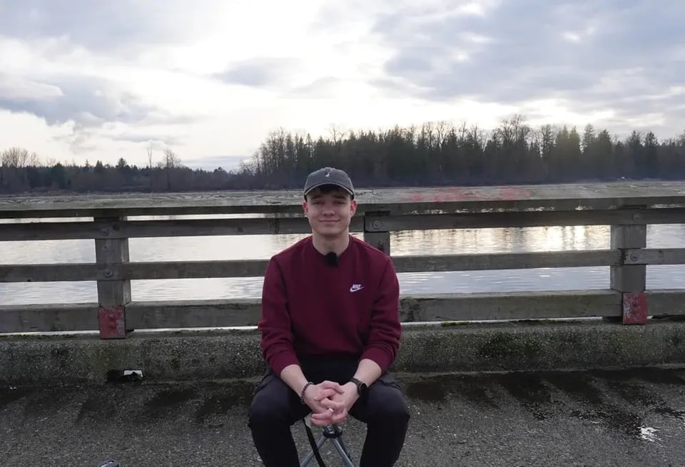 Stefan sitzt auf einem Geländer vor einem Fluss in Kanada