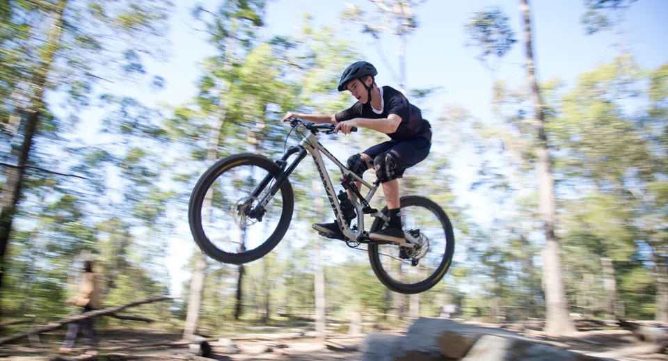 Una persona va in bicicletta attraverso un'area boschiva nel terreno della Nerang State High School.