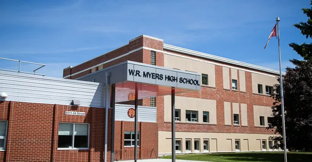 L'edificio della W.R Myers High School con la scritta ben visibile contro il cielo blu e un pennone per la bandiera in primo piano.