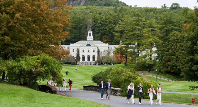 Il campus della Berkshire School mostra un edificio storico circondato da alberi autunnali e persone a passeggio su viali ben tenuti.