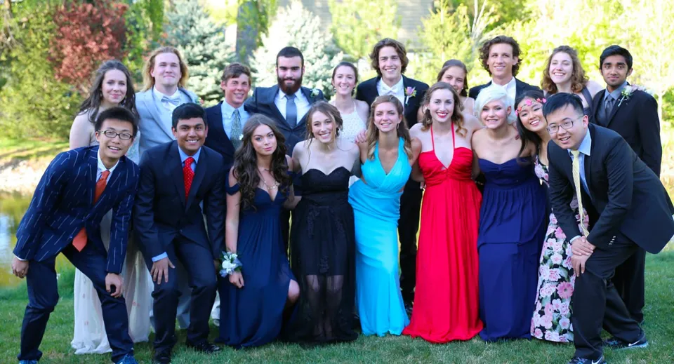 Un gruppo di persone in abiti formali posa insieme all'aperto nel campus della Riverstone International School.