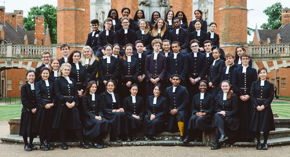 Un gruppo di studenti in abito accademico formale si trova davanti allo storico edificio in mattoni della Christ's Hospital School.