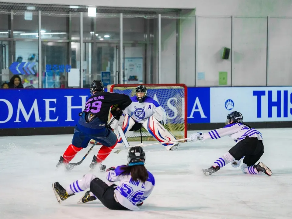 Schüler von Branksome Hall Asia spielen ein Hockeyspiel auf dem Eis mit einem Torwart im Einsatz.