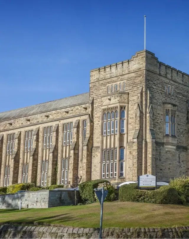 Edificio storico in pietra di una scuola britannica sotto un cielo azzurro