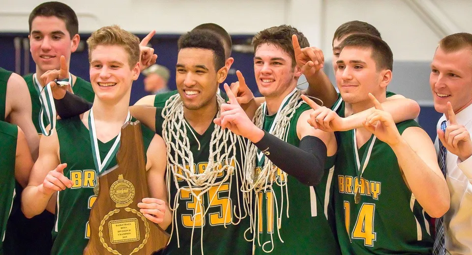 Un gruppo di studenti giocatori di basket della Bishop Brady High School festeggia con una coppa dopo la partita.